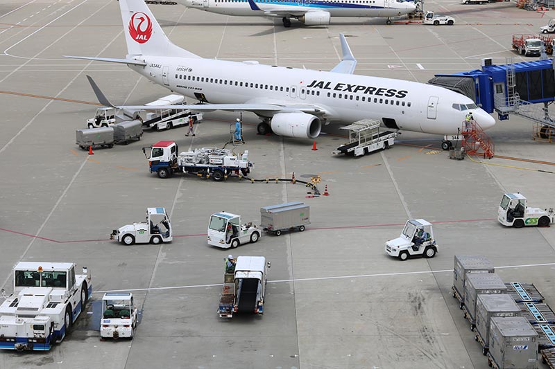 写真：飛行機の機体の周りで働く車たち
