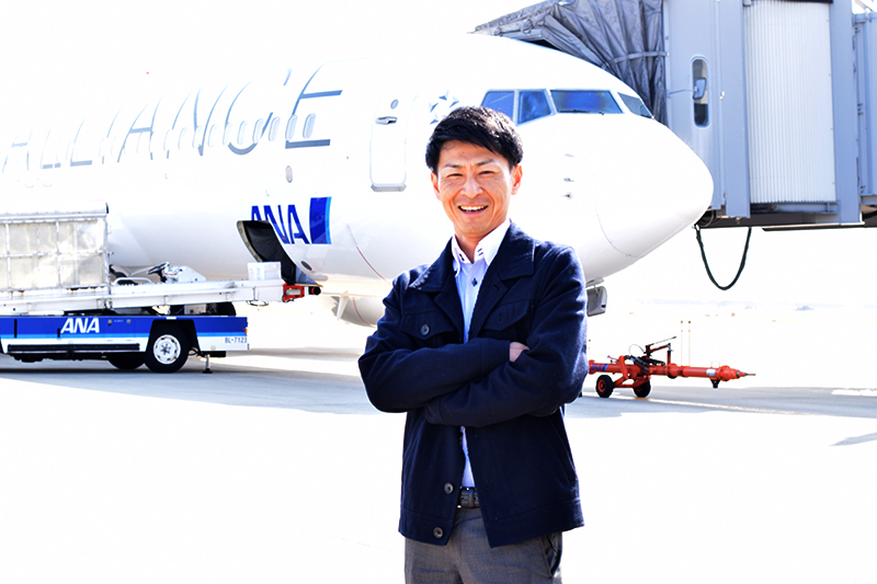 写真：飛行機の前に立つ川崎さん