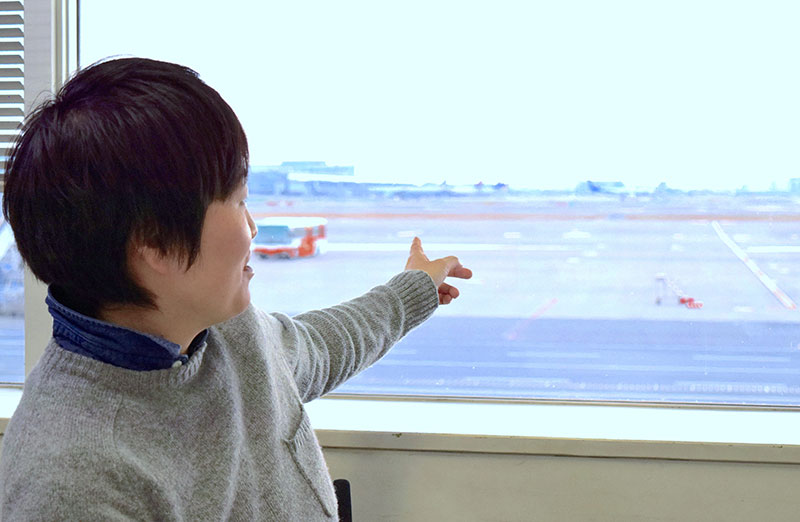 写真：空港を指さす小林さん